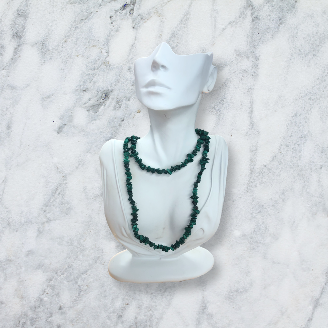 A malachite chip bead necklace with green banded stone chips draped on a white display bust against a marble background from Crystal Gallery